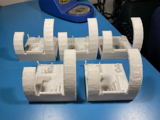 Five of "3d Printer Test Mini" objects, all face up, showing varying degrees of print quality.