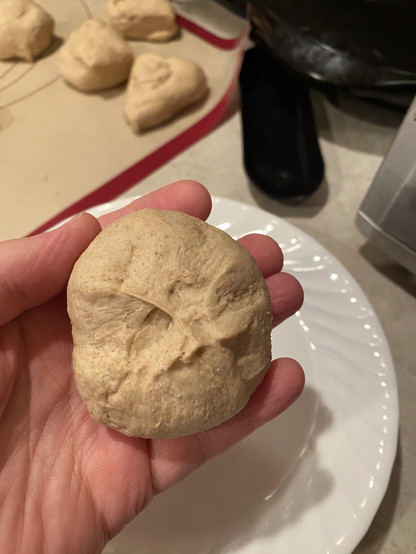 the ball of dough with the flaps opposite the smoothest end pushed back down towards the centre and joined together with fingers. the ball of dough with the flaps opposite the smoothest end pushed back down towards the centre and joined together with fingers.