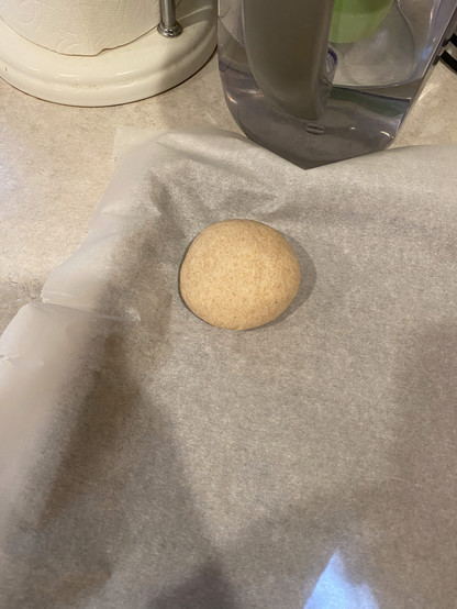 a very smooth bagel dough ball on parchment paper ready to get to rising a very smooth bagel dough ball on parchment paper ready to get to rising