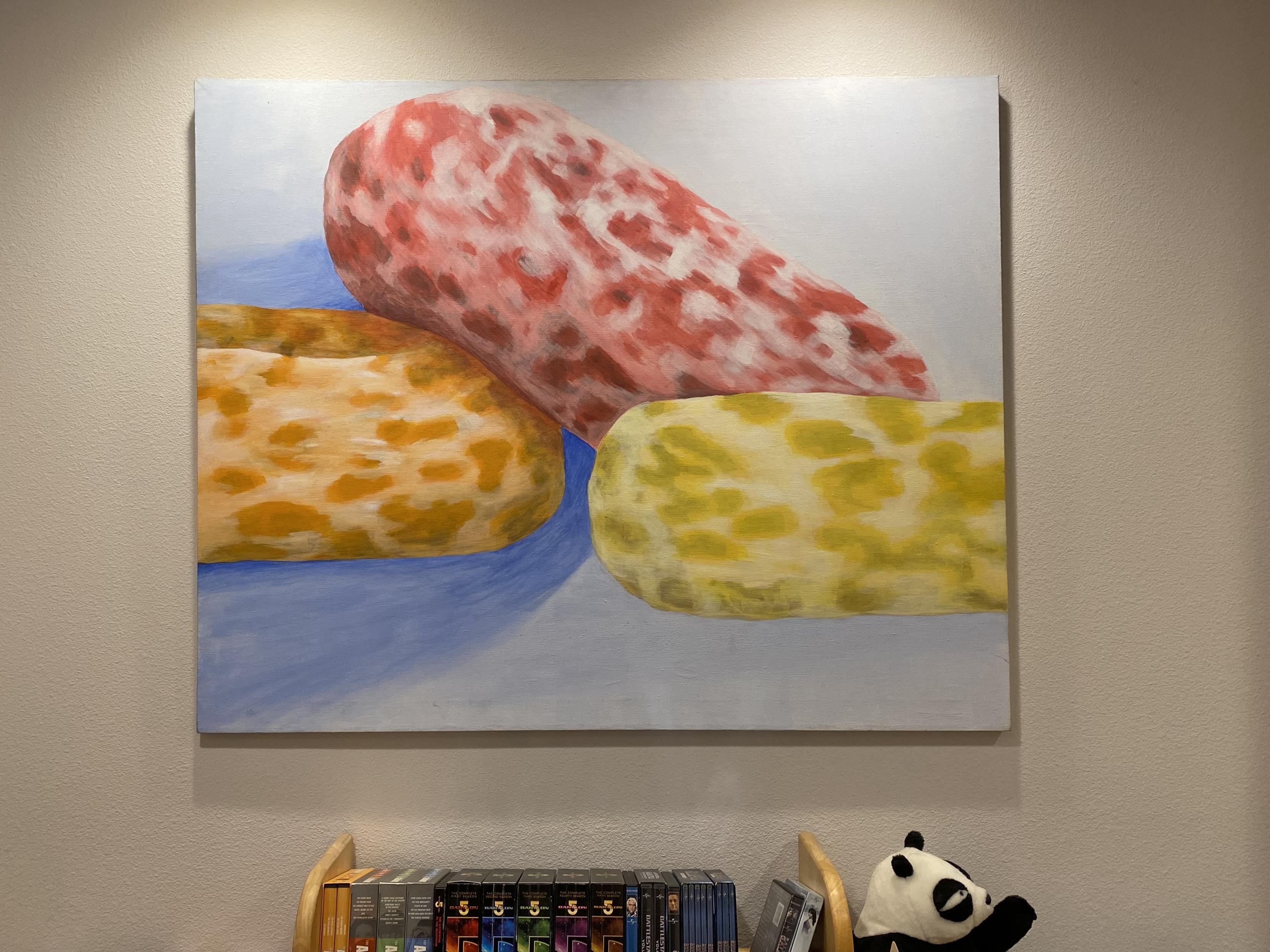 a 5’-wide acrylic painting of three froot loops, giant sized, seen from their sides against a blue background. the shadow is offset because the assignment also required an unusual angle, so I rotated the froot loops 90 degrees. below it on the wall is genma saotome in plush panda form and some The Avengers and Babylon 5 DVDs on a shelf included for scale.