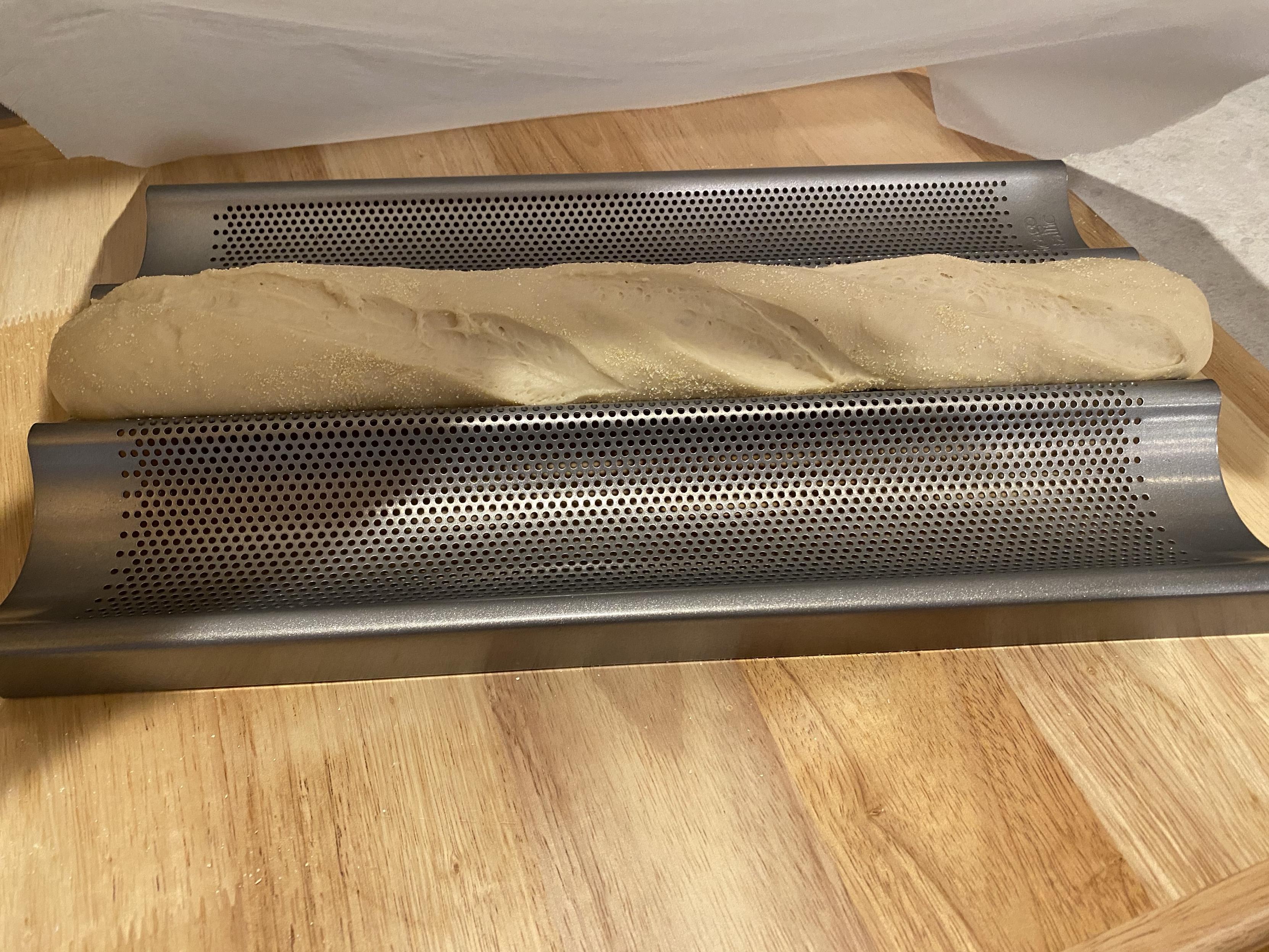 baguette-shaped dough on a baguette tray with three very long cuts