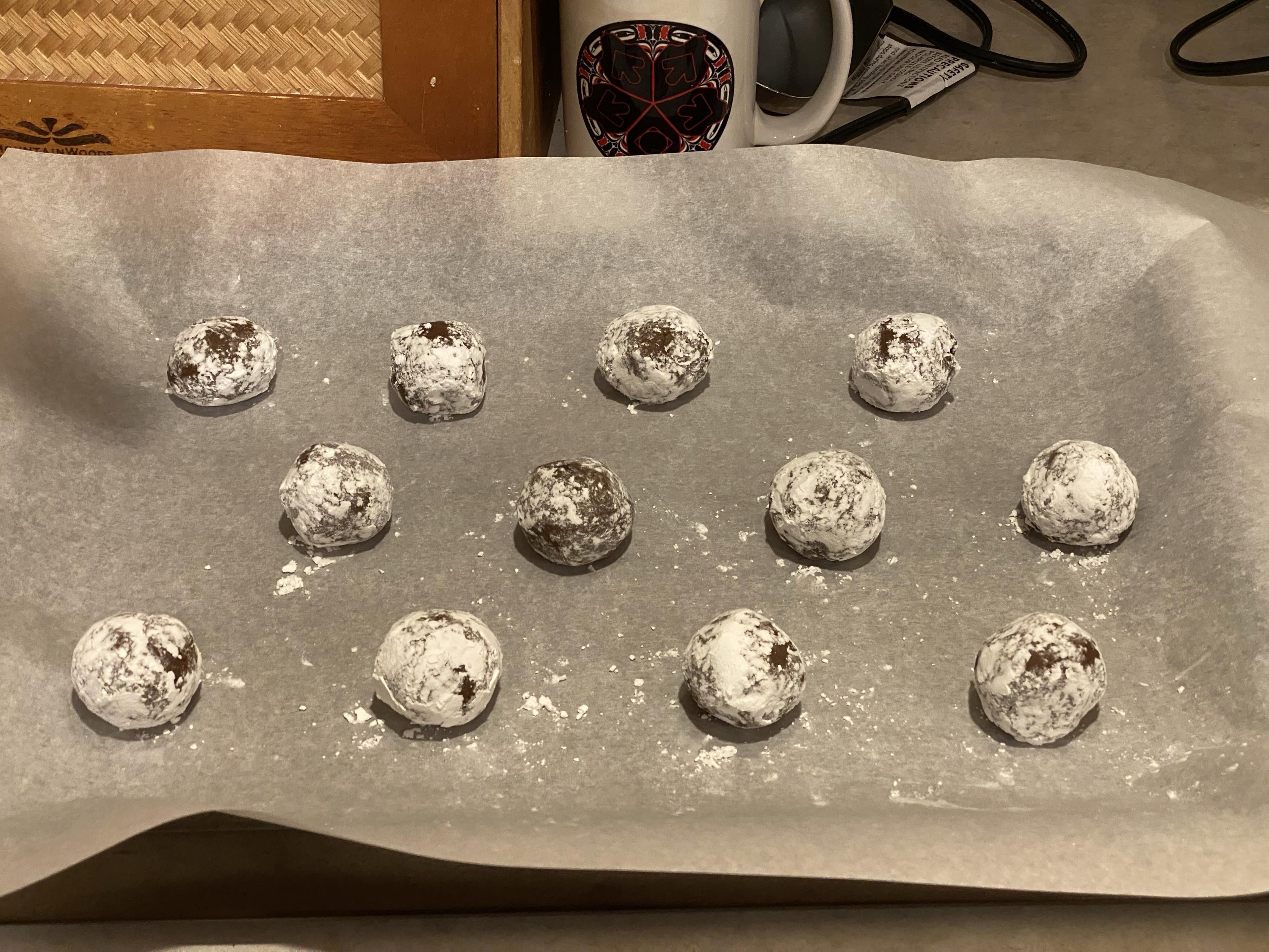 12 balls of sugared cookie dough on parchment paper ready to go into the oven