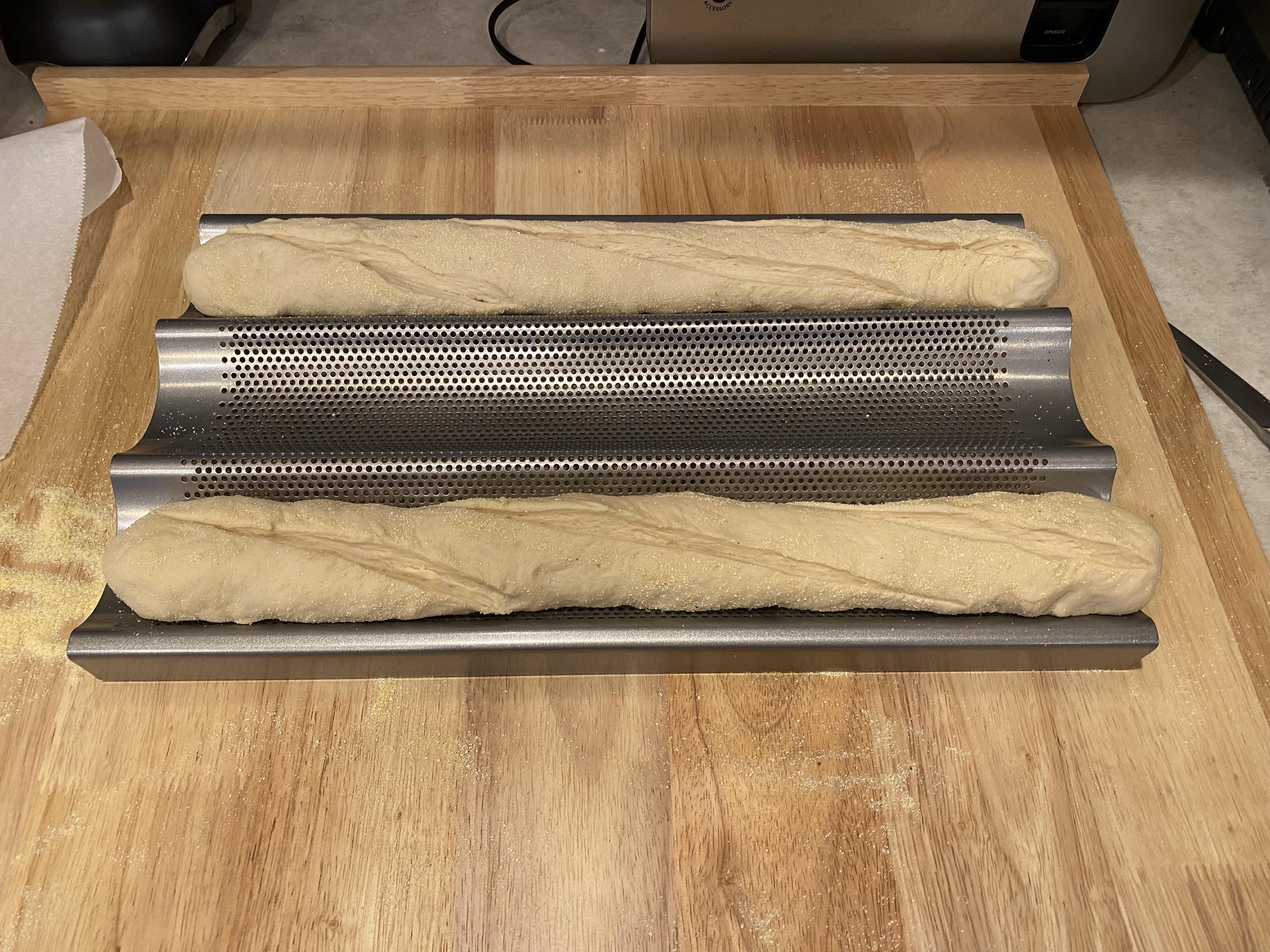 two formed baguettes sliced for rising in their special baking tray