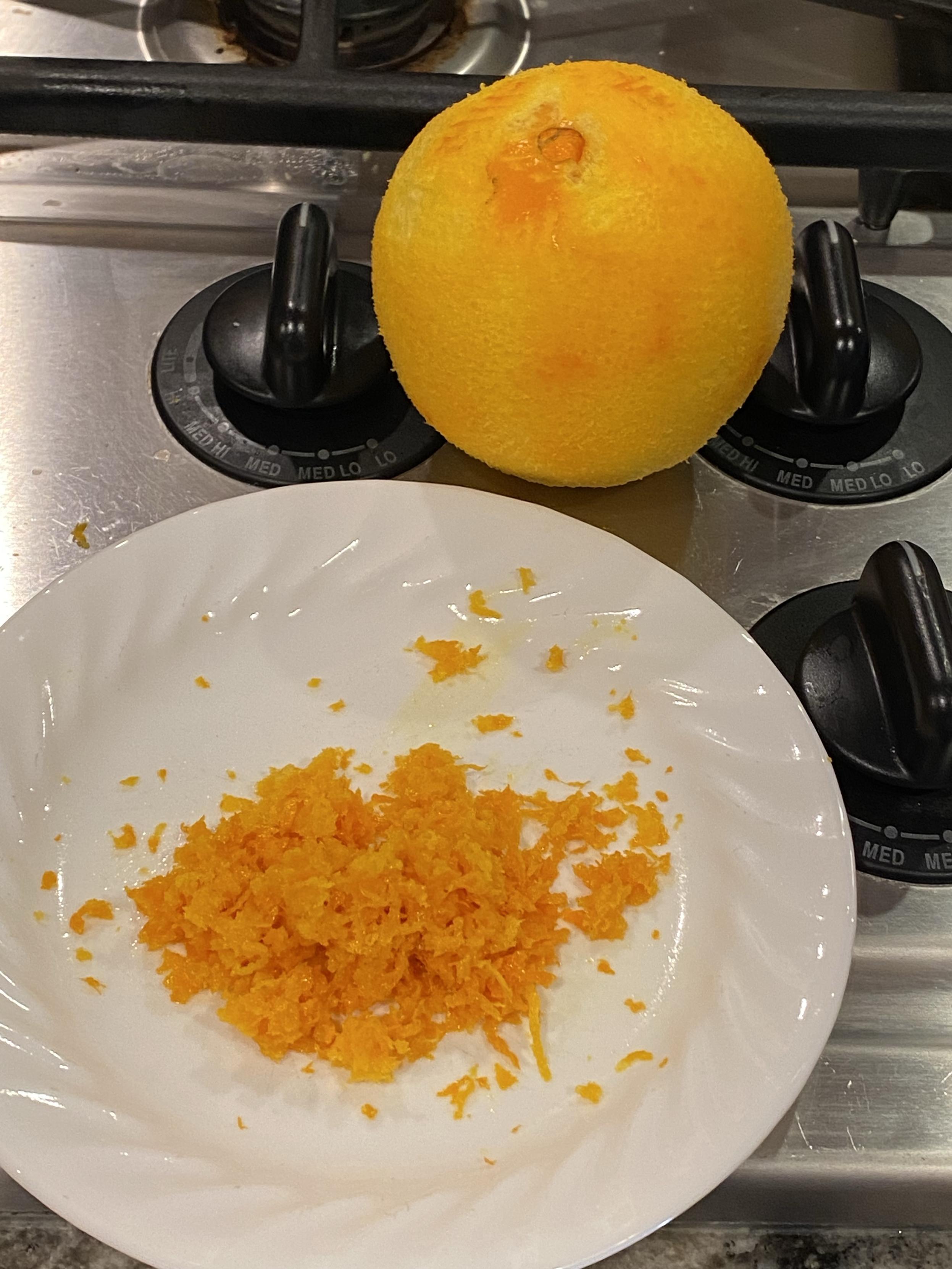 a zested orange and the resulting zest next to it on a plate