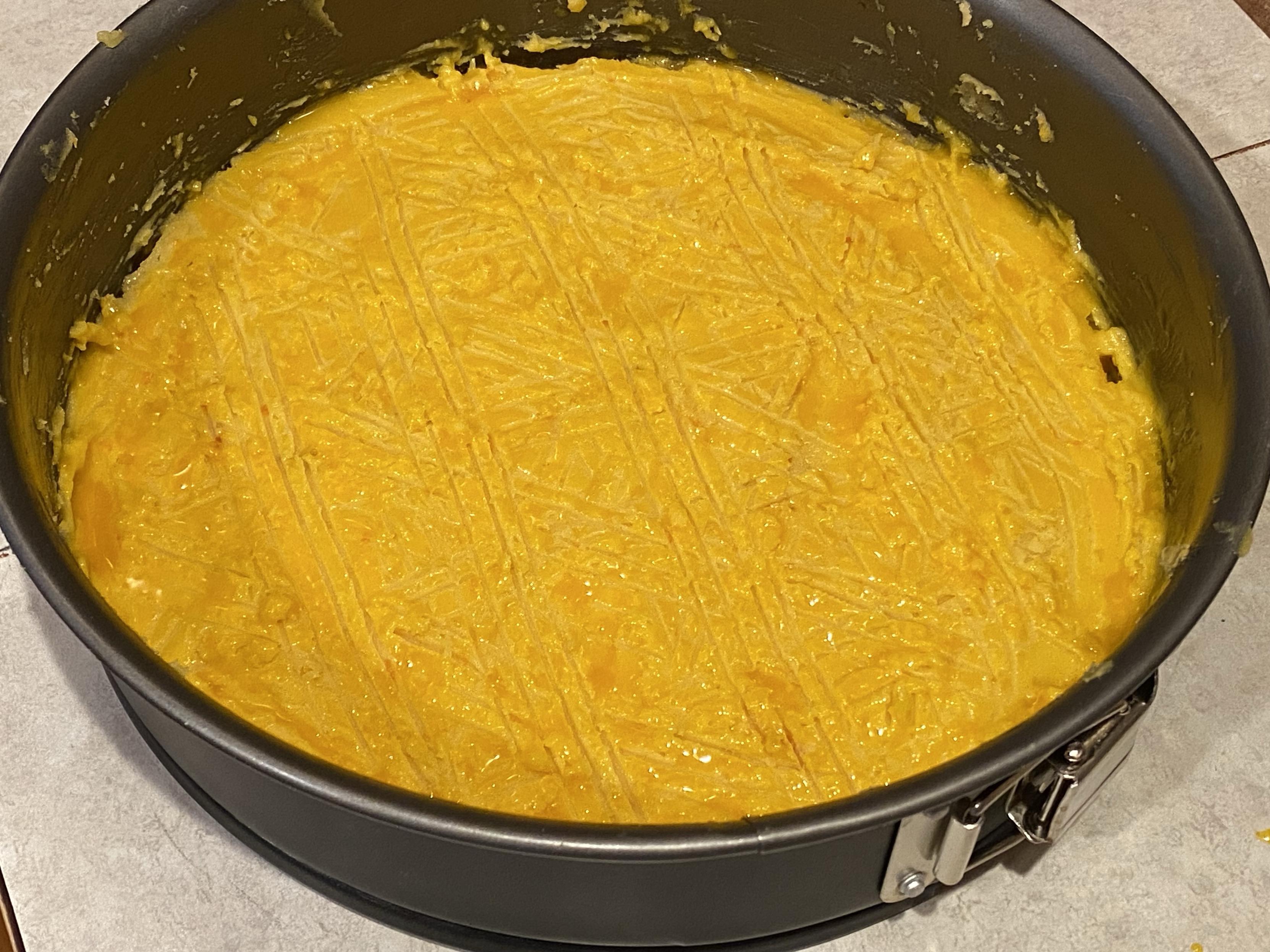 same cake tin but now the batter is coated in egg milk glaze and crosshatched with a fork several times 