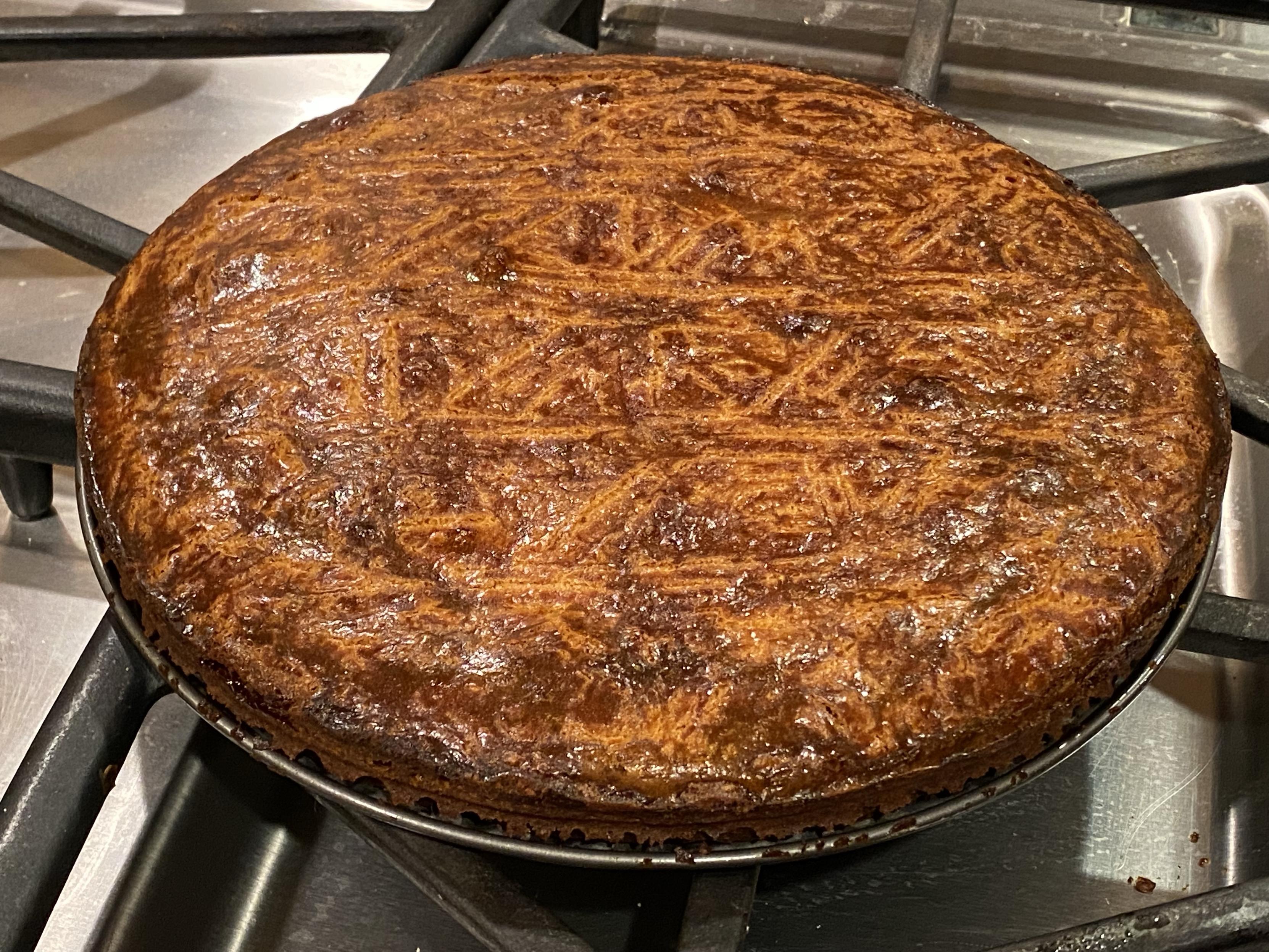 the cake, edges clean, out of pan, sitting on the stovetop, more brown than golden but not entirely not golden either