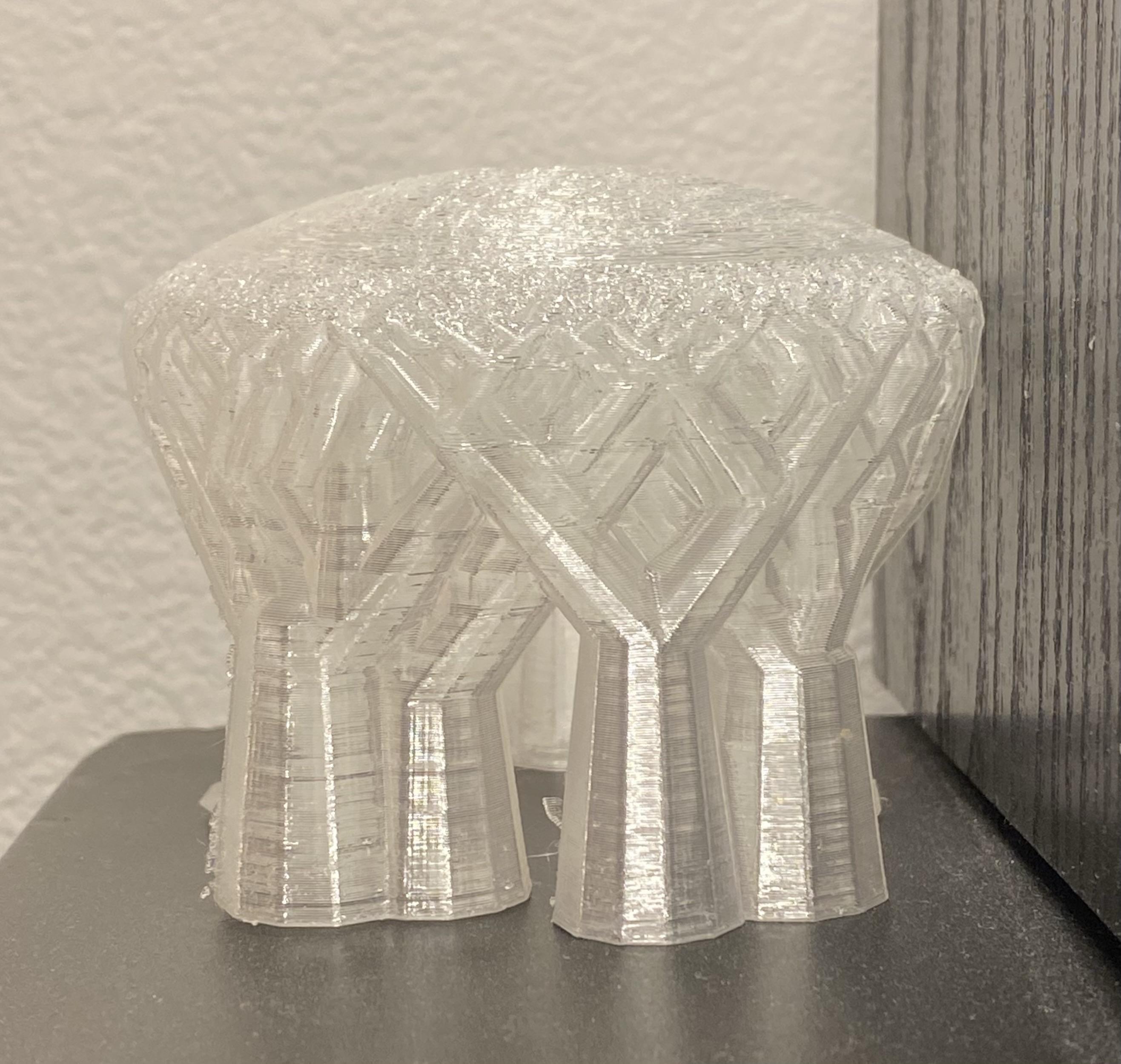 a tree-type dome-topped clear PLA support structure removed in one piece and saved, sitting atop a black cabinet