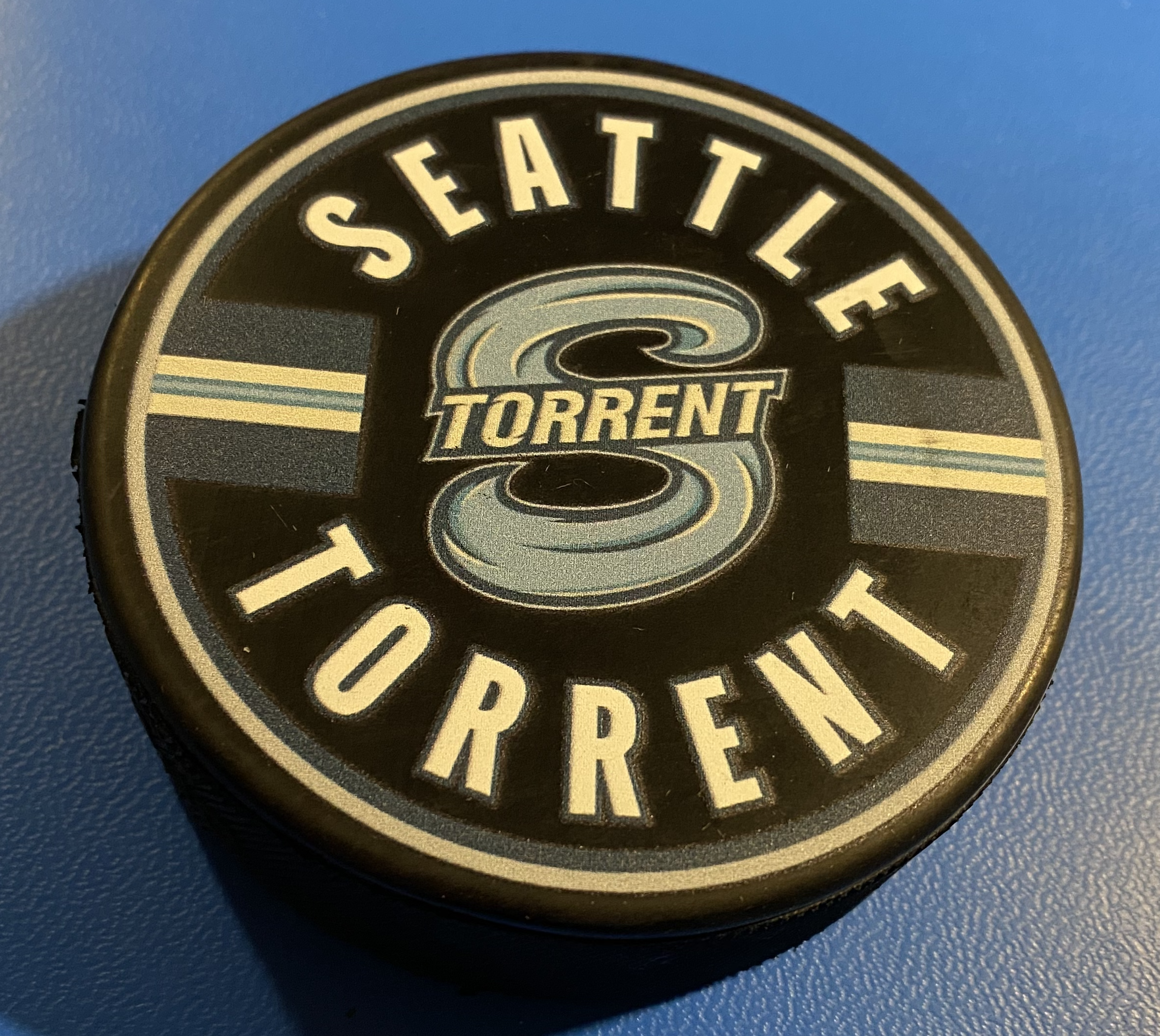 An official Seattle Torrent PWHL merch puck with the Torrent team logo printed in colour on a real puck along with extra stripes