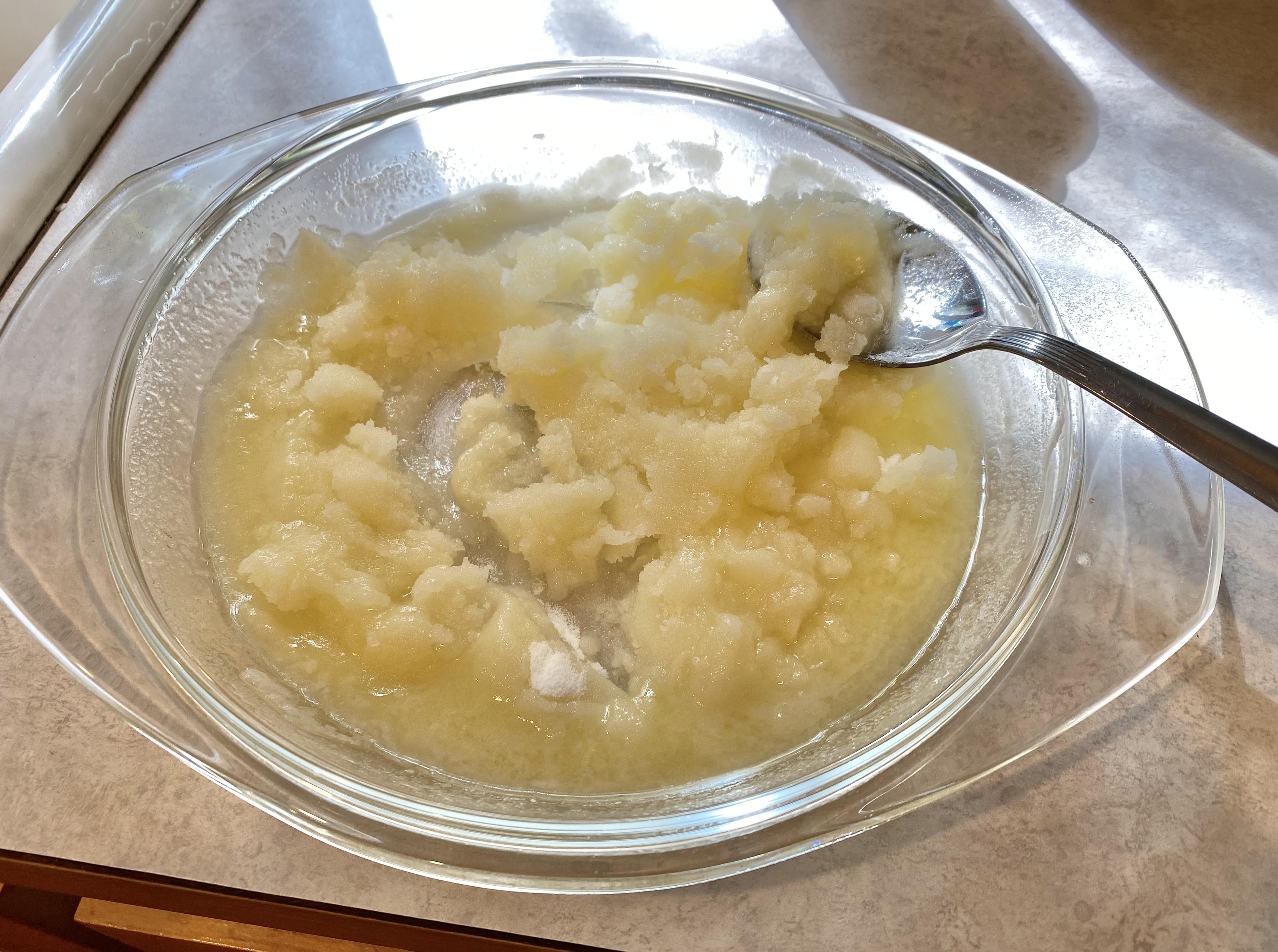 200g mixed partly into the butter in the pie plate, more mixing to come. a metal spoon is also visible.