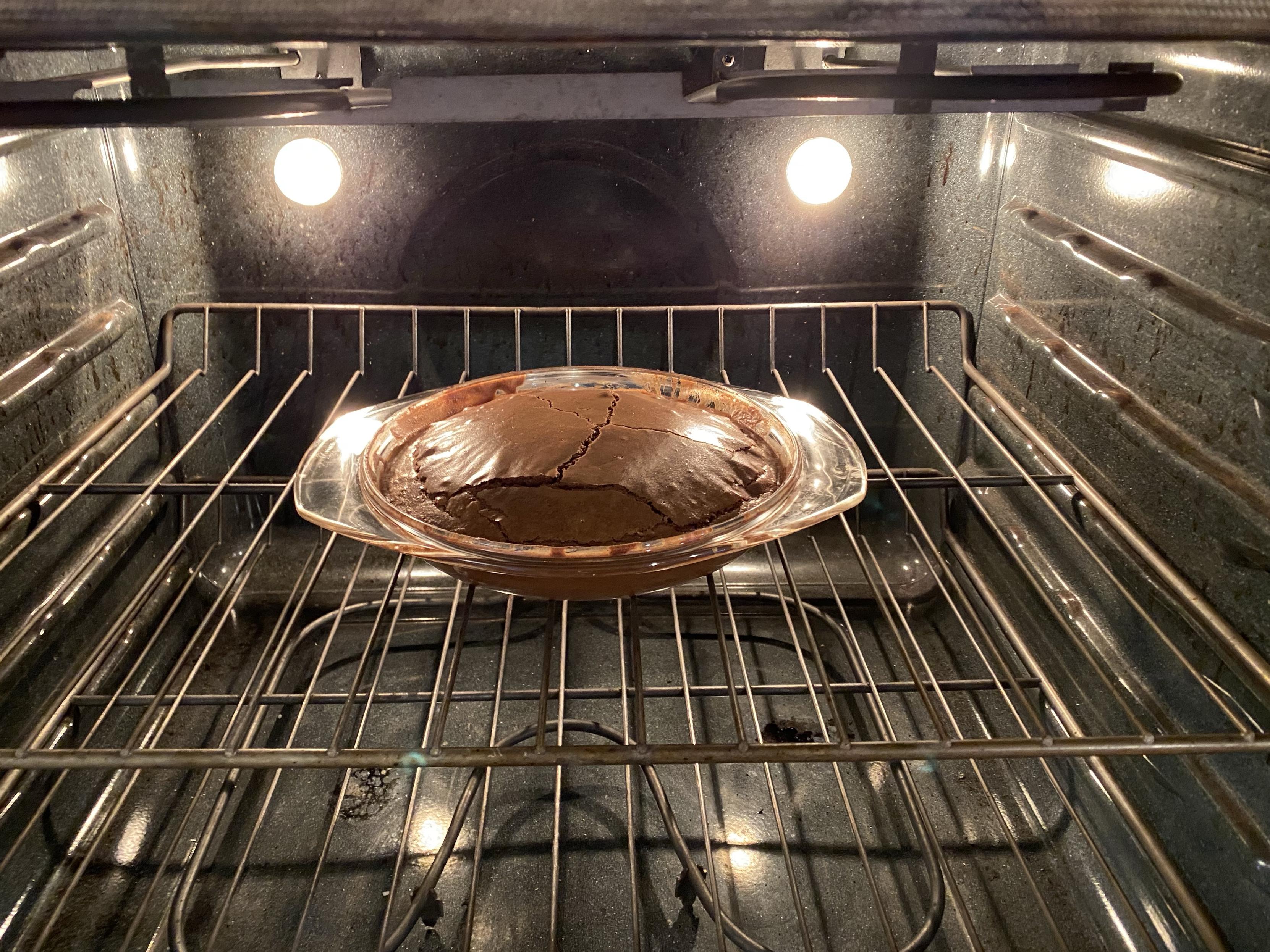 a more risen than expected finished cake in a pie tray. the top layer formed plates which then cracked from expansion
