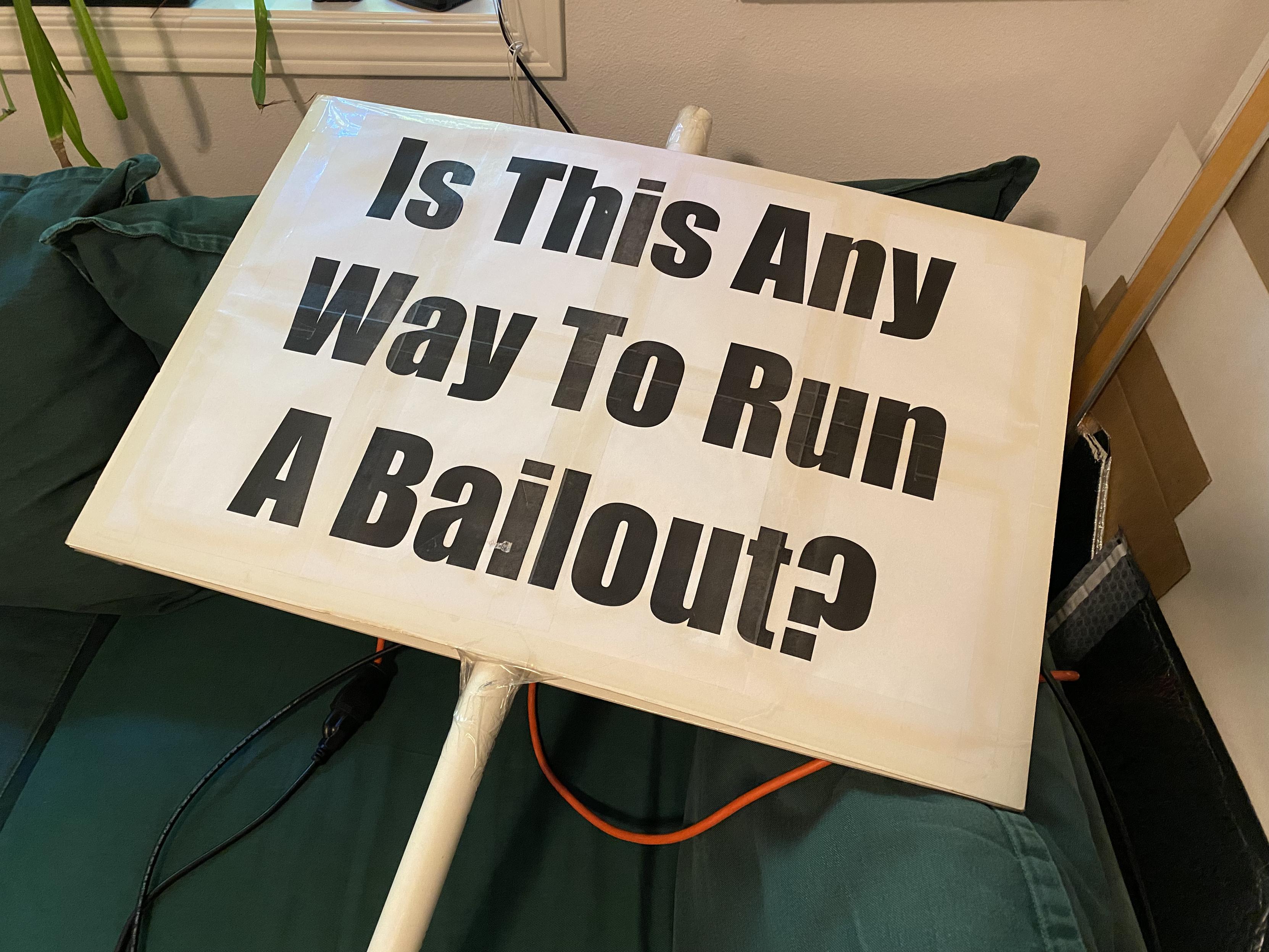 A big and visibly yellowed at the edges protest sign reading "Is This Any Way To Run A Bailout?"