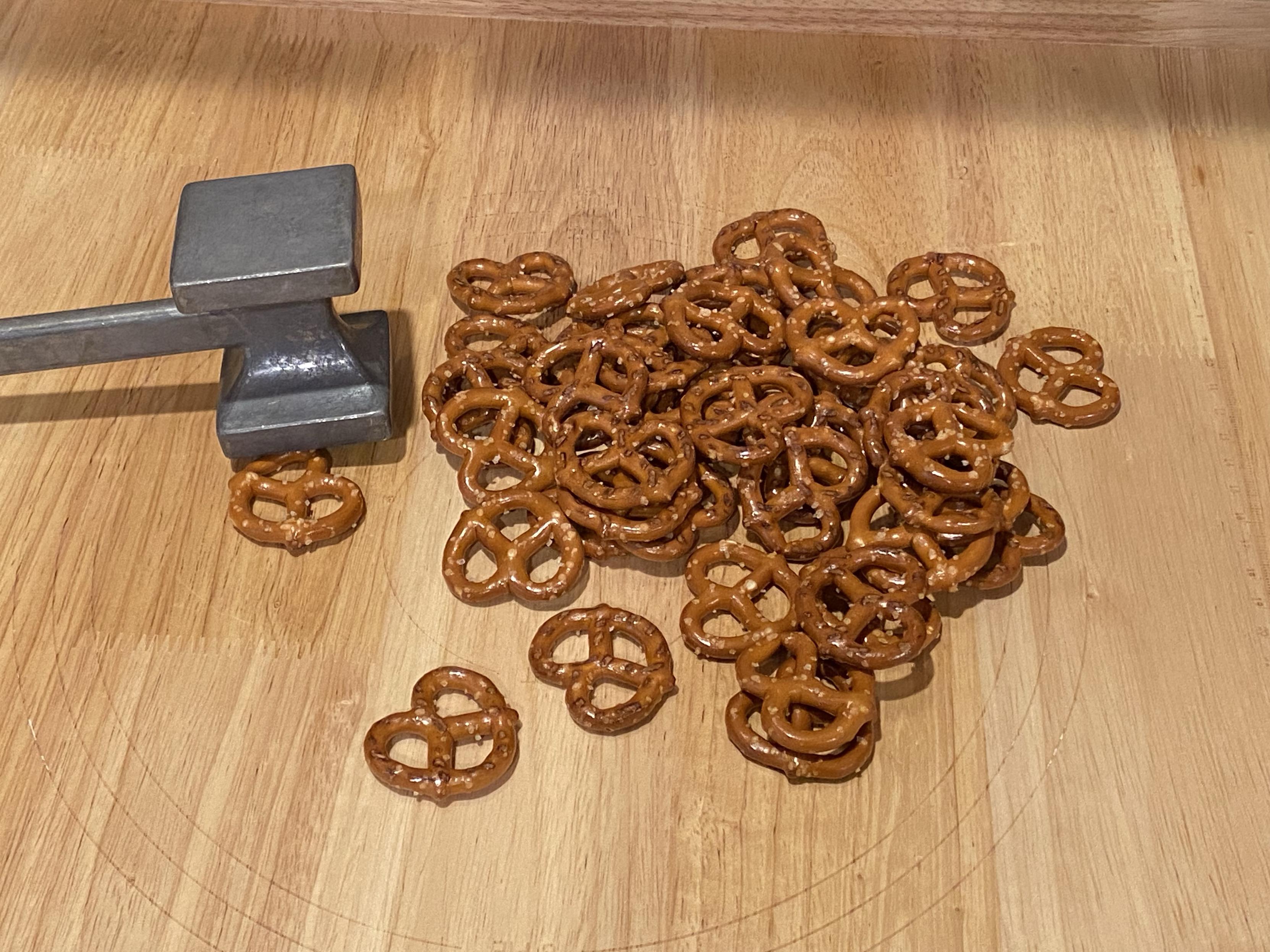 a bunch of pretzels and a tenderising hammer on a board