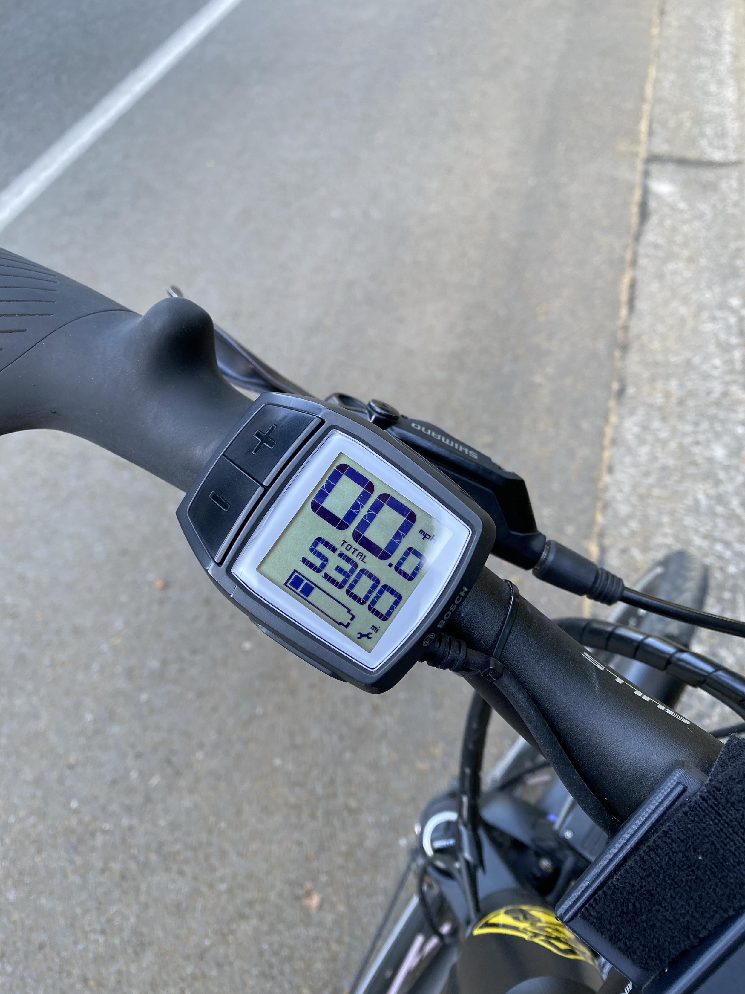 a bike odometer reading 5300 miles with a road and a white stripe divider beyond